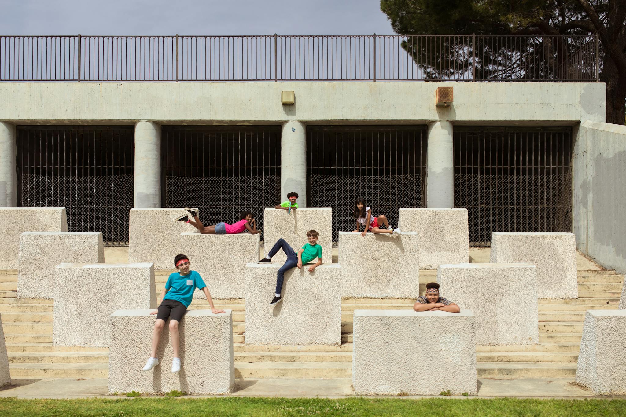 Children enjoying a sunny day outdoors lounging on large concrete blocks in a park.