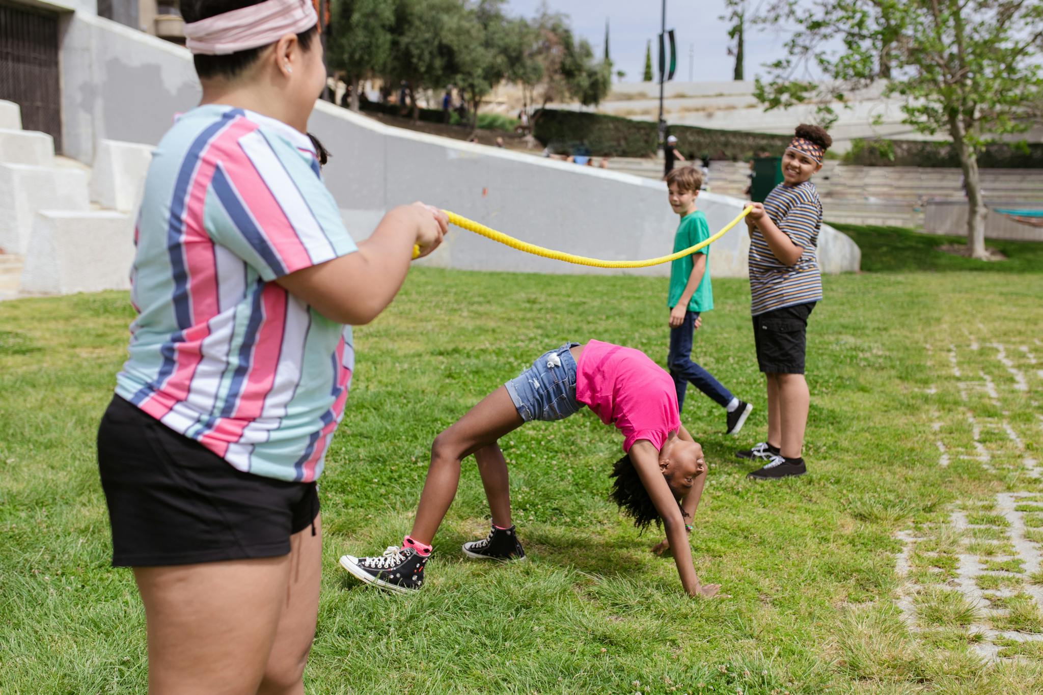 Children enjoying an outdoor limbo game during summer camp activities.