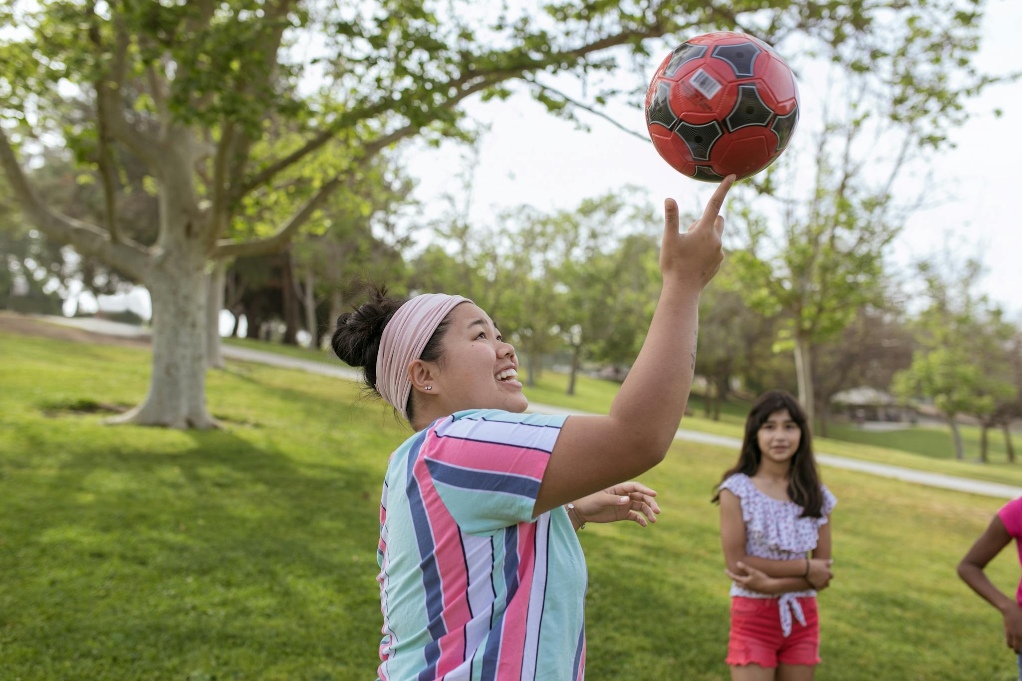 Children joyfully playing with a football in a sunny park during summer camp.